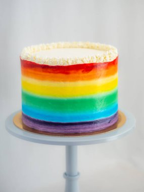 Pasta şefi düğün partisi için lgbt gökkuşağı renginde buzlu kek üzerinde çalışıyor. Doğum günü pastası. Gökkuşağı kağıt bardak kağıtları. Doğum günün kutlu olsun. Tatilleri kutluyoruz. LGBT gururu.