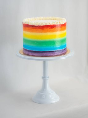 Pasta şefi düğün partisi için lgbt gökkuşağı renginde buzlu kek üzerinde çalışıyor. Doğum günü pastası. Gökkuşağı kağıt bardak kağıtları. Doğum günün kutlu olsun. Tatilleri kutluyoruz. LGBT gururu.