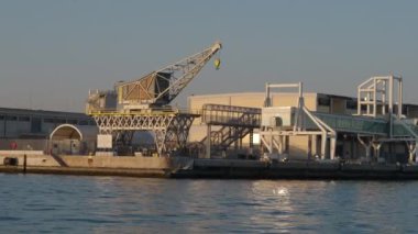 Venedik gölünde iskele tarafındaki vinç. Gün batımında bir tekne görüntüsünden.