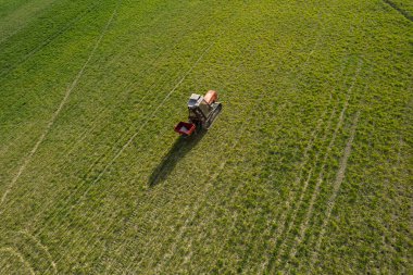 Çiftçi yokuş yukarı sürerken bahar mevsiminde çiftlikte traktör sürüyordu.