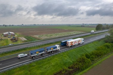 Piacenza, İtalya - Nisan 2023 Kargo kamyonları ve otoyoldaki araçlar a1 otostrada del sole hava manzaralı Padain düz kırsal alanları arasında