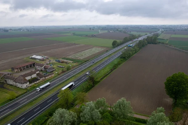 stock image Piacenza, Italy - April 2023 Cargo trucks and cars in the motorway a1 autostrada del sole aerial point of view in between padain plain rural fields