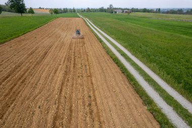 Castell 'Arquato, İtalya - Nisan 2023 Çiftçi tarlada sürünen traktör, havadan bakılmadan önce kuru tarlaya girdi