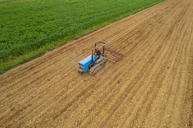 Castell 'Arquato, İtalya - Nisan 2023 Çiftçi tarlada sürünen traktör, havadan bakılmadan önce kuru tarlaya girdi