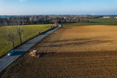 Sürüngen traktörü kullanan çiftçi, geride bir toz bulutunu sürüklüyor, sürme, güç sarsıcı yüzey kabuğu kırılması, bitkilerin kuru toprak üzerinde doğmasını ve tohumlanmasını kolaylaştırıyor.