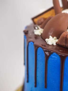 Mavi kremalı pasta makrosu. Kutlama için beyaz arka planda izole edilmiş koyu çikolata kremalı ve karışık şekerli.