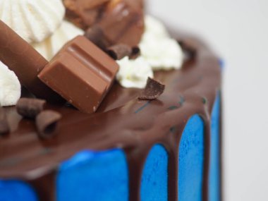 Mavi kremalı pasta makrosu. Kutlama için beyaz arka planda izole edilmiş koyu çikolata kremalı ve karışık şekerli.