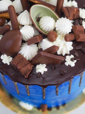 Mavi kremalı pasta makrosu. Kutlama için beyaz arka planda izole edilmiş koyu çikolata kremalı ve karışık şekerli.