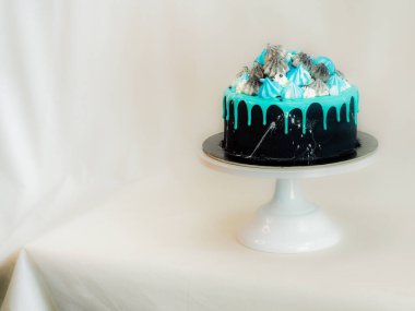 Üzerinde mavi turkuaz damlayan ve renkli el yapımı kremalı pasta stüdyo beyaz izole arka plan.