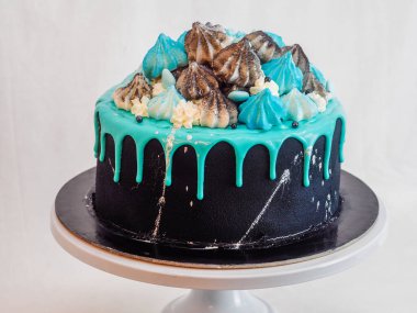 Üzerinde mavi turkuaz damlayan ve renkli el yapımı kremalı pasta stüdyo beyaz izole arka plan.