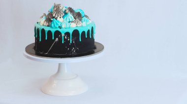 Üzerinde mavi turkuaz damlayan ve renkli el yapımı kremalı pasta stüdyo beyaz izole arka plan.