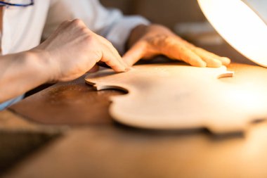 Luthier el yapımı bir kemanın masa üstünü kazıyarak şekil ve sesi optimize ediyor.