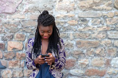 Güzel, Afro-Amerikan bir kadının cep telefonu uygulaması üzerinden dışarıdaki duvarda mesajlara cevap veren portresini kapat.