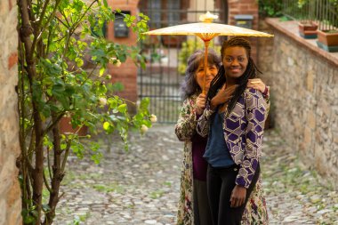 Yazın, eski köyde, açık havada çeşitli çiftler eğleniyor. Komik bir ifade. LGBT göze çarpıyor.