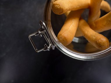 Karışık tahıllı İtalyan Breadstix Grissini stüdyonun tepesinde. Siyah arka plandaki cam kavanozda izole edilmiş..
