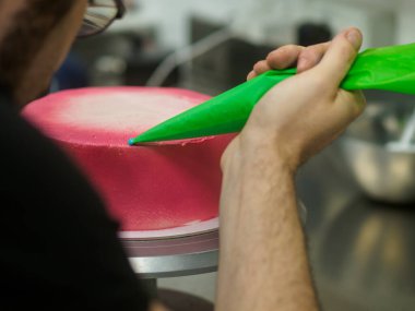 Aşçı kremalı, pembe fincanlı kek hazırlıyor. Tatlı serpiştirmeli ve tek boynuzlu at soslu.