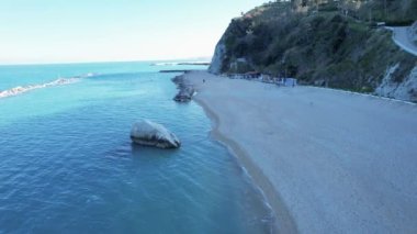 Adriyatik Denizi 'nin dalgaları Sasso del Bo kayası ve küçük çakıl taşları kumsalında kırılıyor. İnsansız hava aracı görüntüleri. Numana, İtalya. Genel Görünüm.