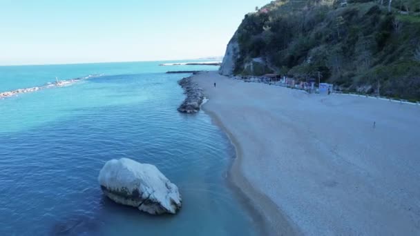 サッソ ボー岩と小さな小石のビーチ ドローン映像でアドリア海の波が砕けています イタリアのヌマナ オーバーヘッドビュー — ストック動画
