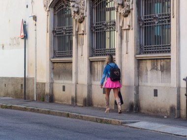 Cremona, İtalya - 22 Haziran 2023 Yaz mevsiminde sokaklarda pembe kısa etekli ve uzun deri çizmeli bir kadın