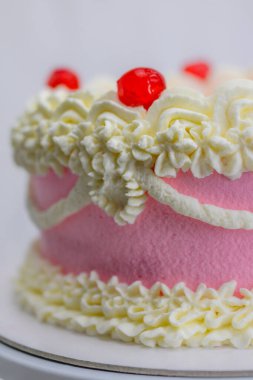 Doğum günü kutlaması için pembe kırmızı kek. Beyaz tenli, spatulayla yumuşatıcı, profesyonel mutfakta eldiven takıyor.