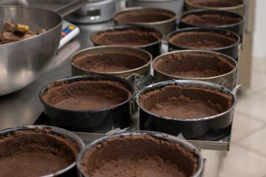 Pasta şefi, profesyonel mutfakta tuzlu karamel peynirli kek için grup çikolatası hazırlıyor ve pişiriyor.