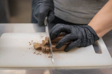 Cheesecake hazırlamak için çikolatalı şekerleme kesen şef. Yakın çekim, yemek servisi yapan profesyonel mutfak.