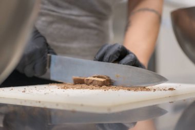 Cheesecake hazırlamak için çikolatalı şekerleme kesen şef. Yakın çekim, yemek servisi yapan profesyonel mutfak.