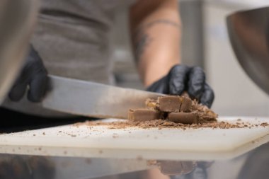 Cheesecake hazırlamak için çikolatalı şekerleme kesen şef. Yakın çekim, yemek servisi yapan profesyonel mutfak.