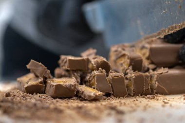 Cheesecake hazırlamak için çikolatalı şekerleme kesen şef. Yakın çekim, yemek servisi yapan profesyonel mutfak.