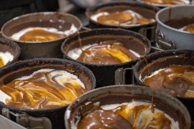 Pasta şefi, profesyonel mutfakta tuzlu karamel peynirli kek için grup çikolatası hazırlıyor ve pişiriyor.