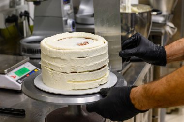 Pasta şefi, profesyonel mutfakta doğum günü pastası olarak çilekli ve yaban mersinli pasta yapıyor.