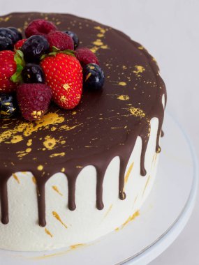 Buzlu pasta, çikolata kaplı, çilekli ve yaban mersinli sos, özel bir kutlama için altın rengi boya.