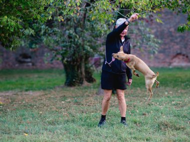 Kısa saçlı, sağlıklı bir kadın antrenman yapar ve köpek yavrusuyla oynardı. Sabahları dışarı atlardı.