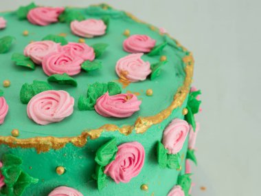 Stüdyoda izole edilmiş şekildeki süslemeleri süsleyen şeker hamuru gülleri ve incilerle kaplı yeşil kremalı pasta.