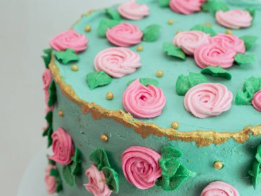 Stüdyoda izole edilmiş şekildeki süslemeleri süsleyen şeker hamuru gülleri ve incilerle kaplı yeşil kremalı pasta.