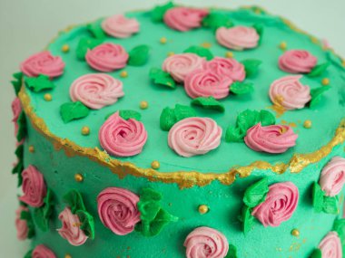 Stüdyoda izole edilmiş şekildeki süslemeleri süsleyen şeker hamuru gülleri ve incilerle kaplı yeşil kremalı pasta.