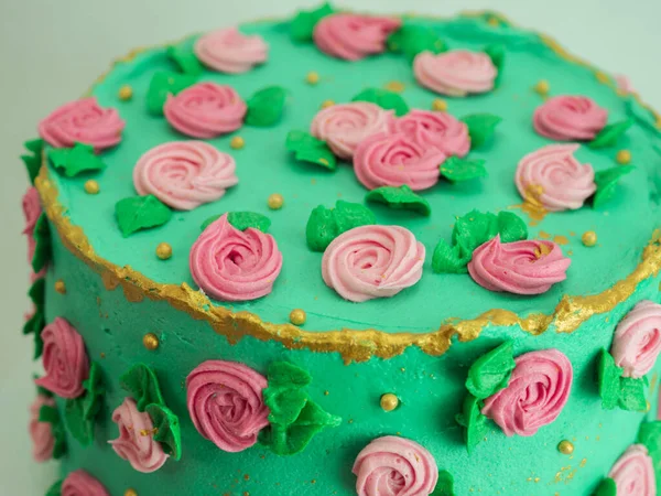 green icing frosted cake with sugar paste roses and pearls topping decoration all around the shape isolated on studio