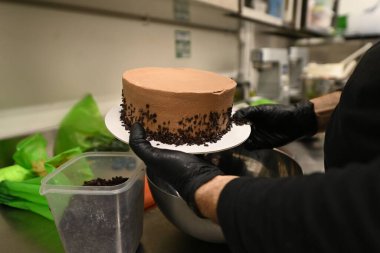 Pasta şefi, profesyonel mutfakta katmanlı kremalı çikolatalı pasta süsledi.