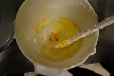 Pasta şefi, profesyonel bir mutfak manzarasında dondurulmuş kek hazırlamak için yenilebilir renkli peynir kremi ve spatula hazırlayın.