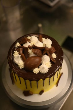 Pasta şefi, profesyonel mutfakta katmanlı kremalı çikolatalı pasta süsledi.