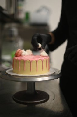 Dondurulmuş taze krema damlayan pembe vanilyalı doğum günü pastası üzerine altın işaretli makaron süslemesi.