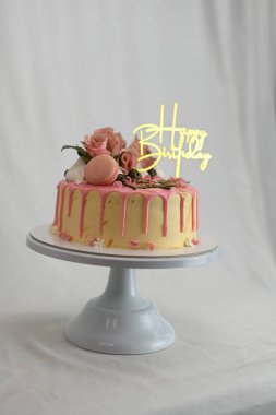 Taze krema damlayan pembe vanilyalı pasta gerçek güller ve üzerinde altın işareti olan badem kurabiyesi.