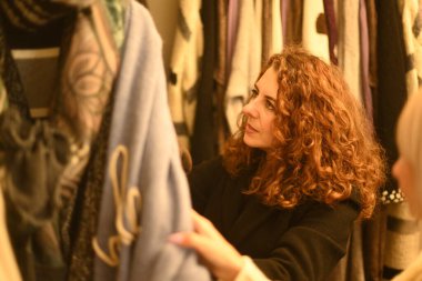 Sarışın genç kadın ve kızıl saçlı en iyi arkadaş moda mağazasında kışın indirimli kıyafet seçiyorlar.