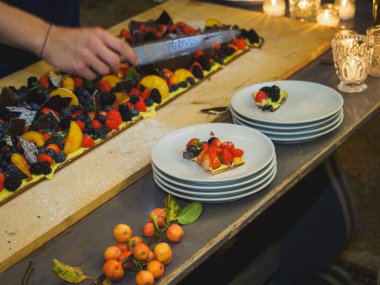 Ahşap bir masa taze pişmiş kısa hamurlu pastayla sunulur. Renkli ve taze meyvelerle kaplı büyük bir pasta. Meyve, kivi ve şeftali gibi..