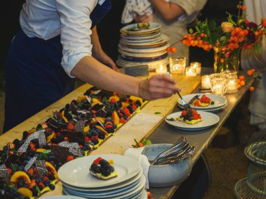 Ahşap bir masa taze pişmiş kısa hamurlu pastayla sunulur. Renkli ve taze meyvelerle kaplı büyük bir pasta. Meyve, kivi ve şeftali gibi..