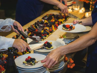 Ahşap bir masa taze pişmiş kısa hamurlu pastayla sunulur. Renkli ve taze meyvelerle kaplı büyük bir pasta. Meyve, kivi ve şeftali gibi..