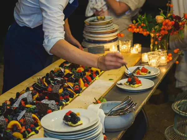 Ahşap bir masa taze pişmiş kısa hamurlu pastayla sunulur. Renkli ve taze meyvelerle kaplı büyük bir pasta. Meyve, kivi ve şeftali gibi..