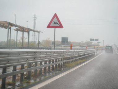 Piacenza, Italy -April 22nd 2024 A highway scene under an overcast sky featuring cars and trucks with road signs and an overpass, rainy day on Motorway A1