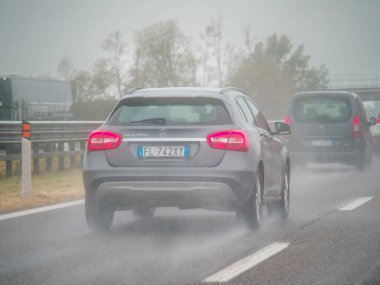 Piacenza, Italy -April 22nd 2024 A highway scene under an overcast sky featuring cars and trucks with road signs and an overpass, rainy day on Motorway A1