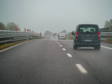 Piacenza, Italy -April 22nd 2024 A highway scene under an overcast sky featuring cars and trucks with road signs and an overpass, rainy day on Motorway A1